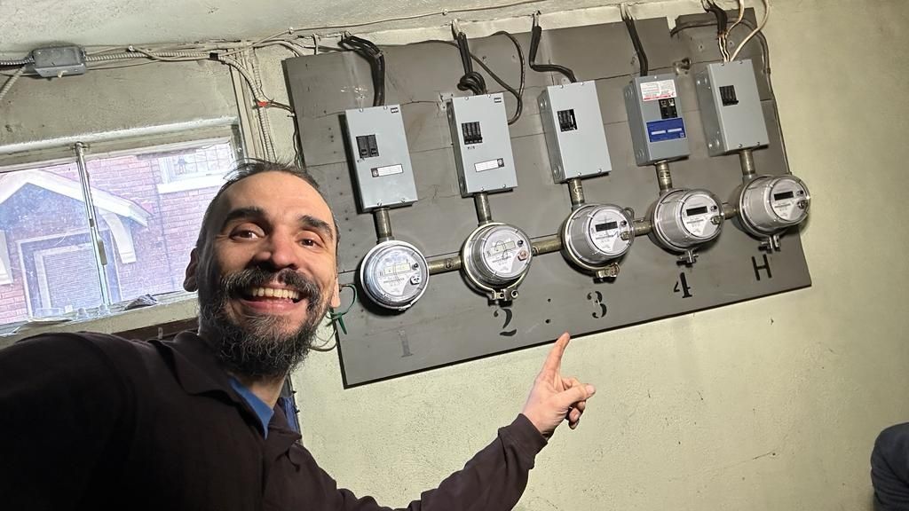 Gabriel pointing to a multi-unit electric meter bank