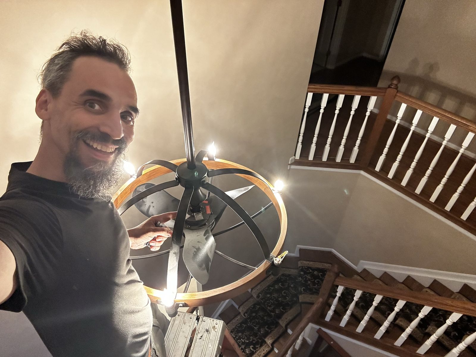 Gabriel with a newly installed ring chandelier over a stairwell