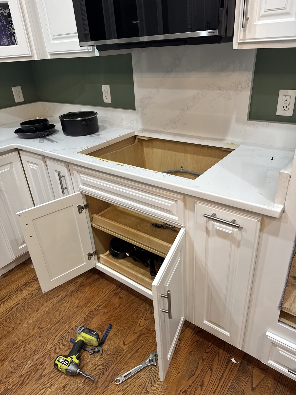 Kitchen sink cabinet opened up for under-sink plumbing work