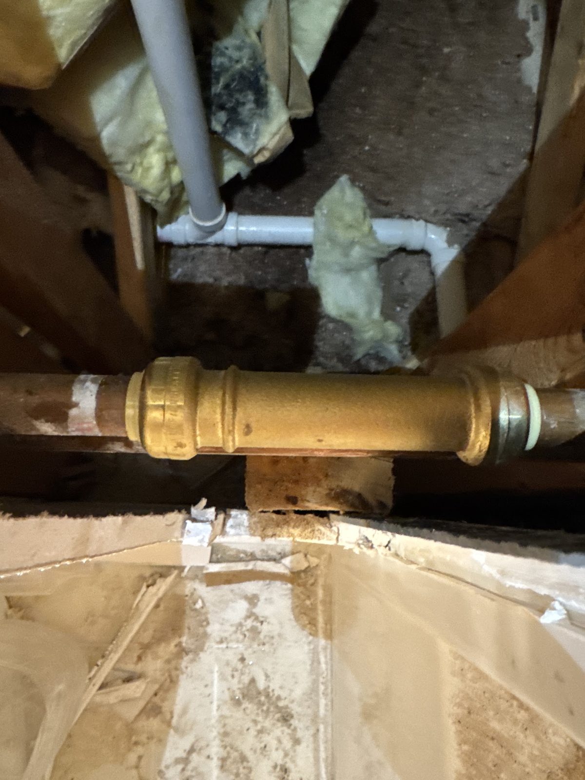 PVC drain piping and brass fitting under the floor