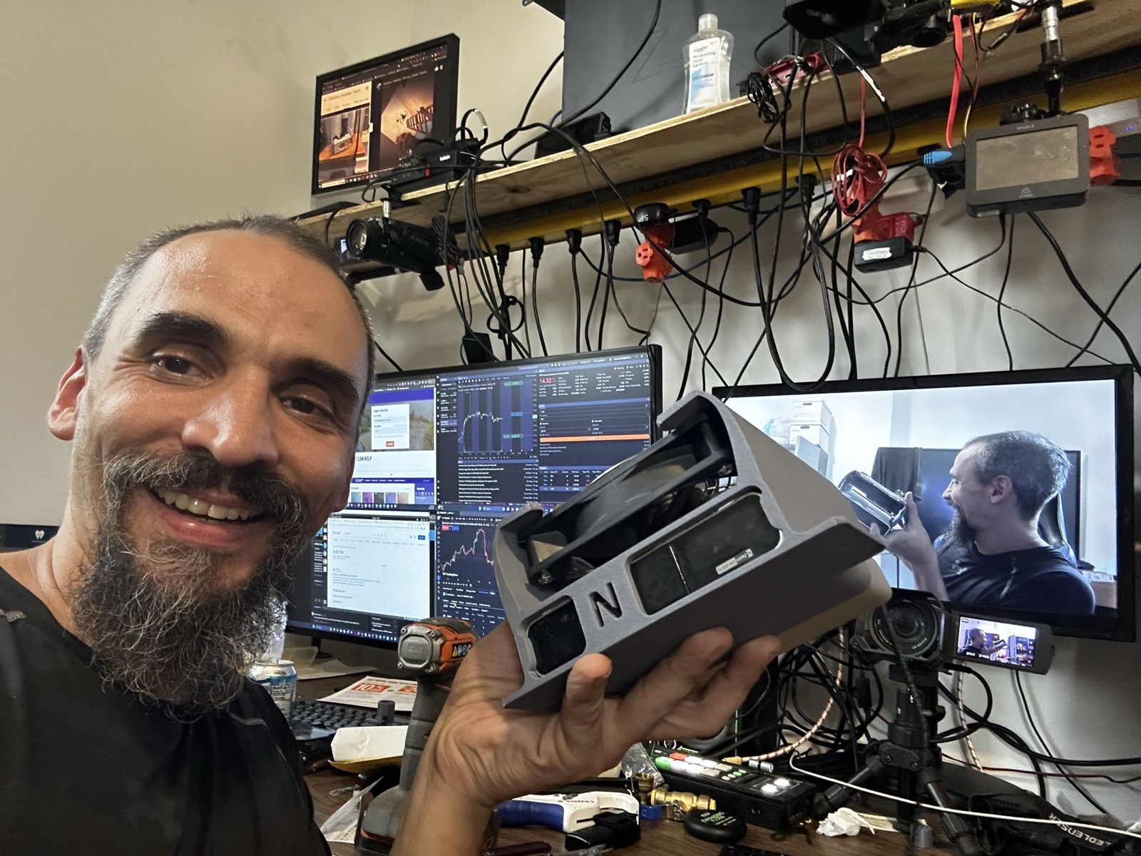 Gabriel at a workbench with live CCTV camera feeds on the monitors