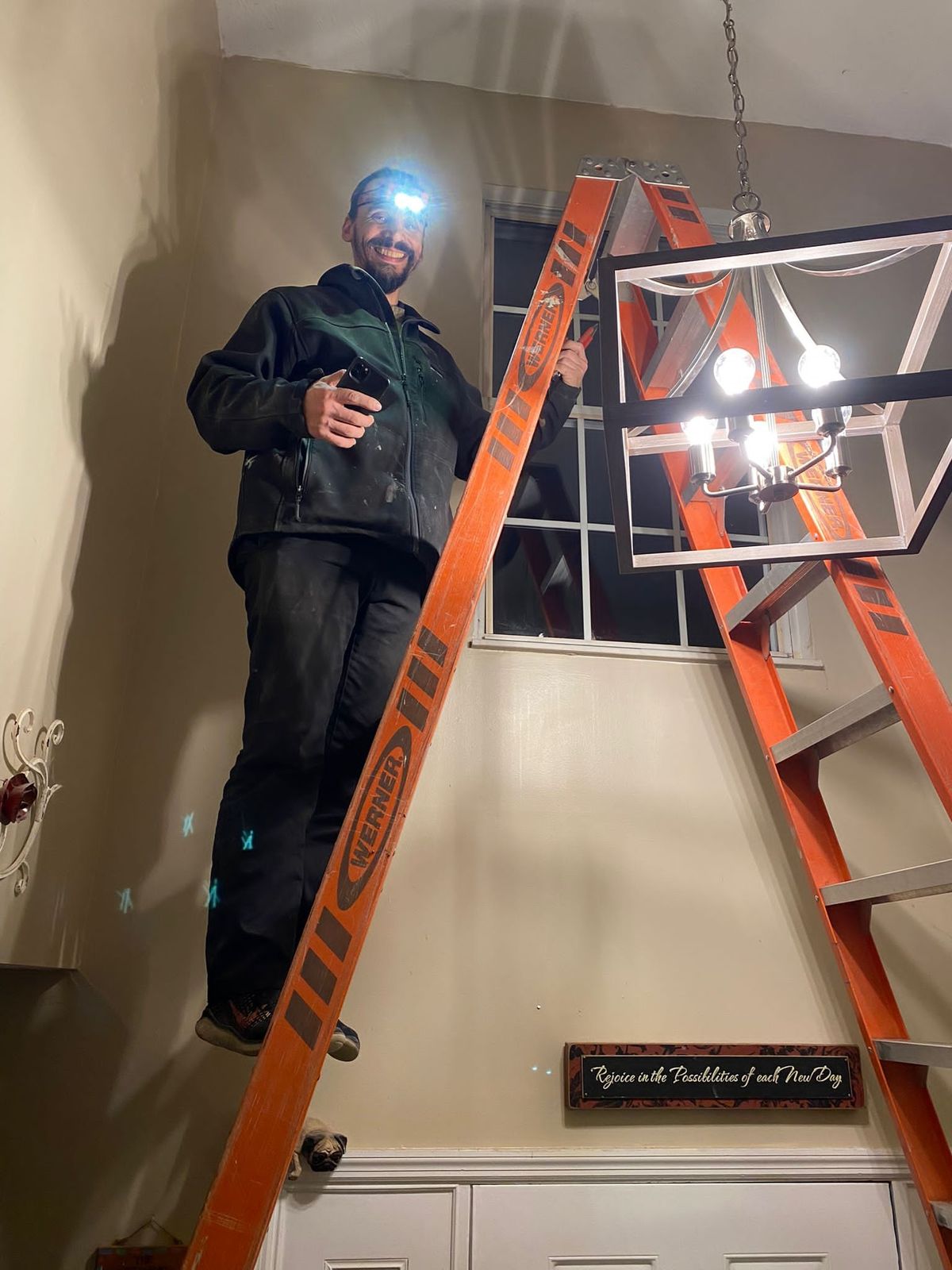 Gabriel on a ladder installing a foyer chandelier