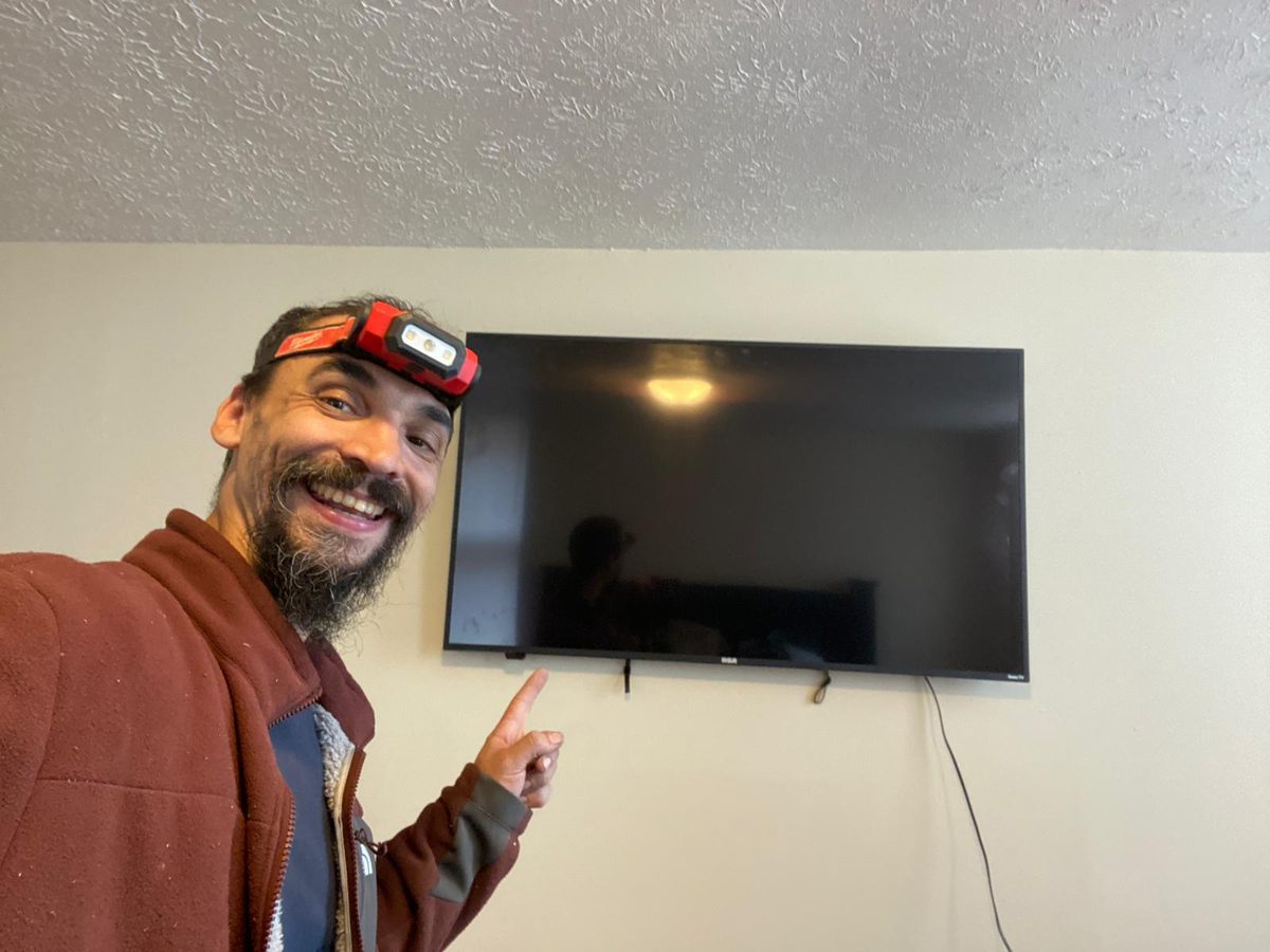 Gabriel next to a flat-screen TV he wall-mounted in a living room