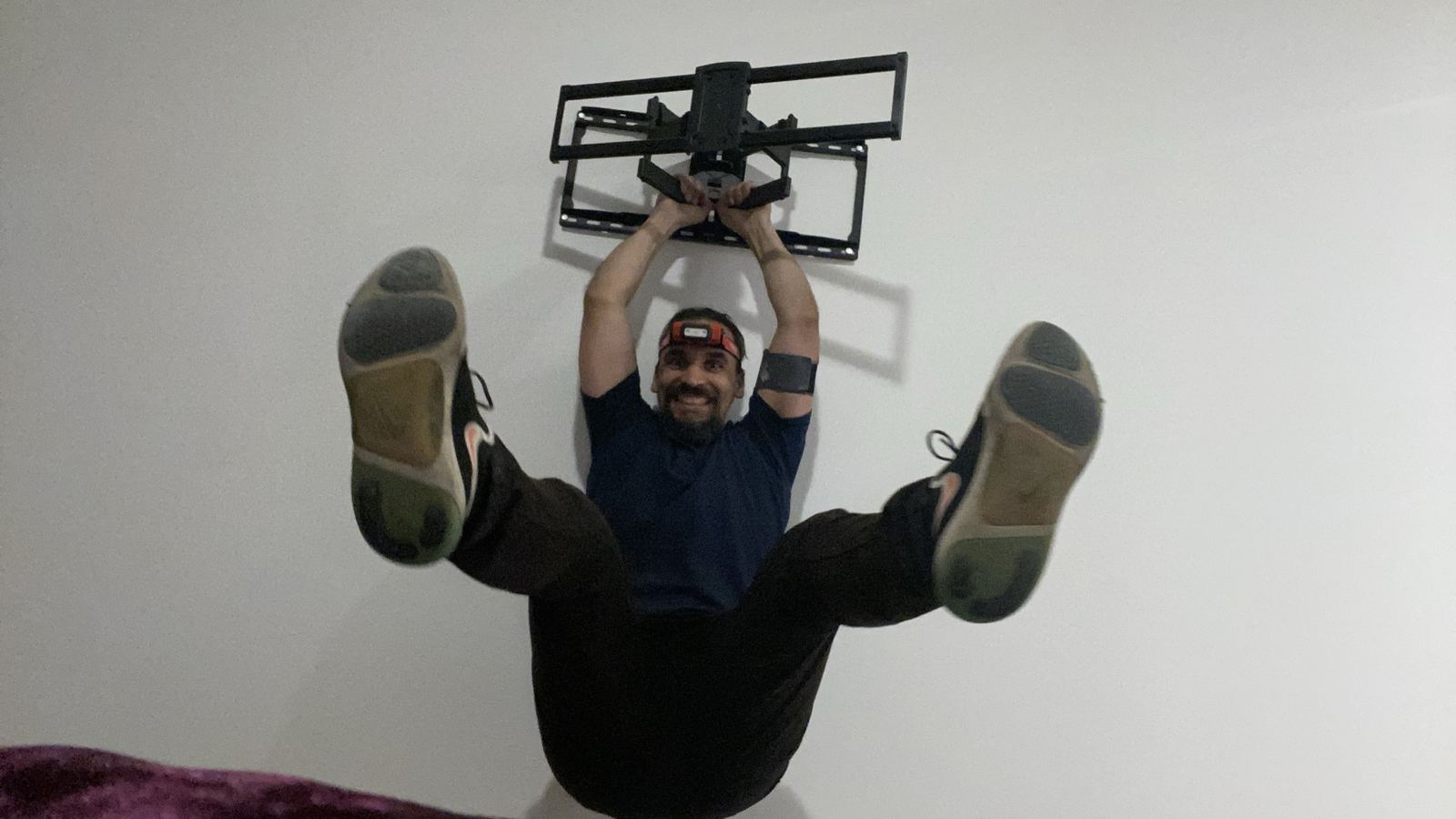 Gabriel strength-testing a TV wall mount in a bedroom