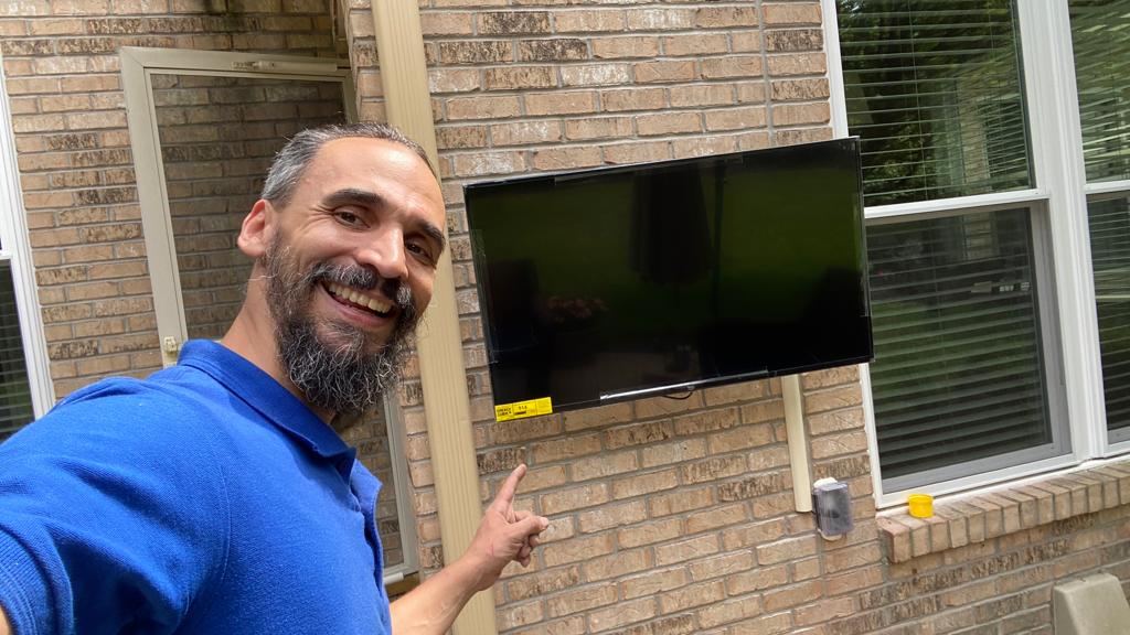 Gabriel with an outdoor TV mounted on a brick patio wall