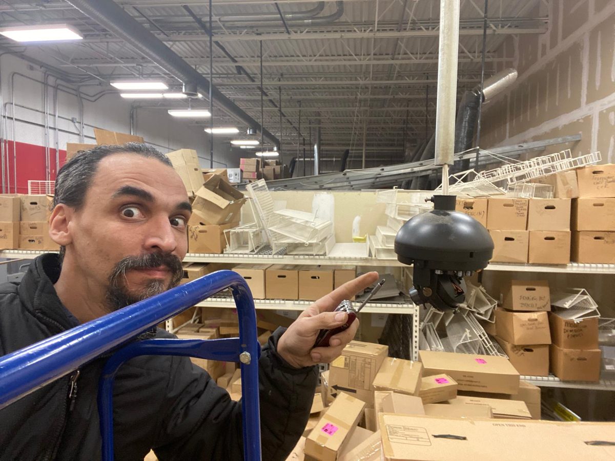 Gabriel pointing at a dome security camera in a warehouse