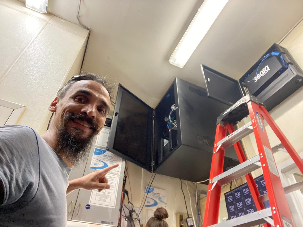 Gabriel by monitors and a ladder at a camera system install